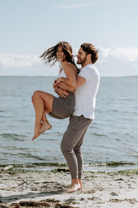 A man holding a woman in his arms and swinging her around playfully on the beach