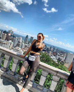 A woman standing against a railing with a city skyline behind her