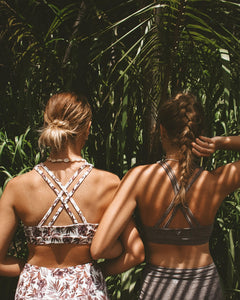 Two women standing with their backs turned and arms interlocked