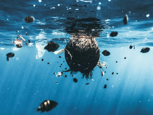 plastic and garbage floating in the ocean surrounded by swimming fish