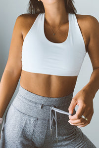 A woman wearing a white contrast bra and heather joggers